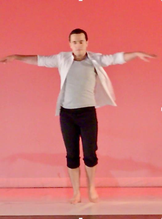 A student jumps in the air before a bright coral background.