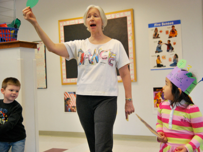 A white woman with gray hair, wearing a white tshirt that reads 