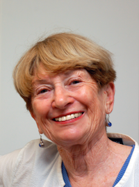 A a headshot of Naima smiling, she is white with blonde hair and is wearing a white shirt.