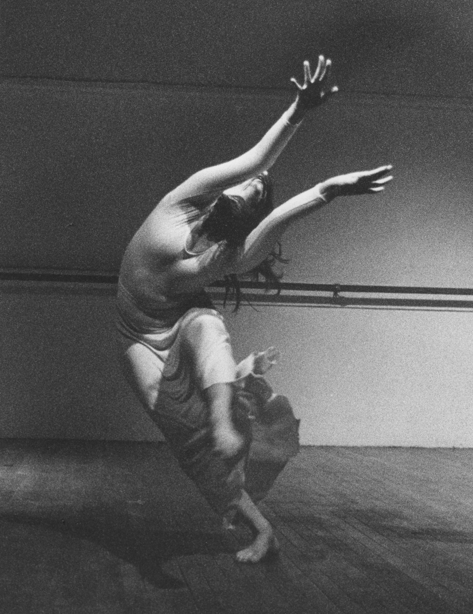 A black and white photo of heather in all white, mid movement, with her arms outstretched.