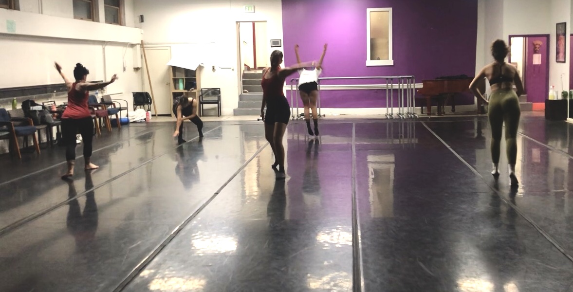 A small group of dancers in a dance studio all around the space looking like they are improving.