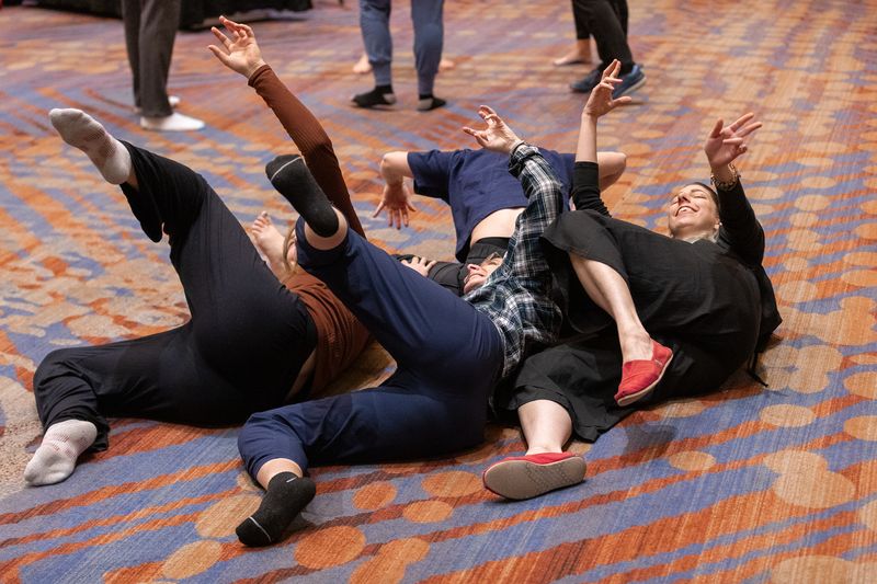 four dance educators lay on their sides with their leg and arm lifted at the 2023 national conference